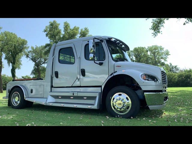 Silver truck parked on grassy field.